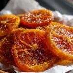 Close-up of glistening Candied Orange Slices with Cinnamon Sugar piled on white parchment paper.