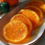Close-up of glistening Candied Orange Slices with Vanilla Syrup arranged on a white platter.