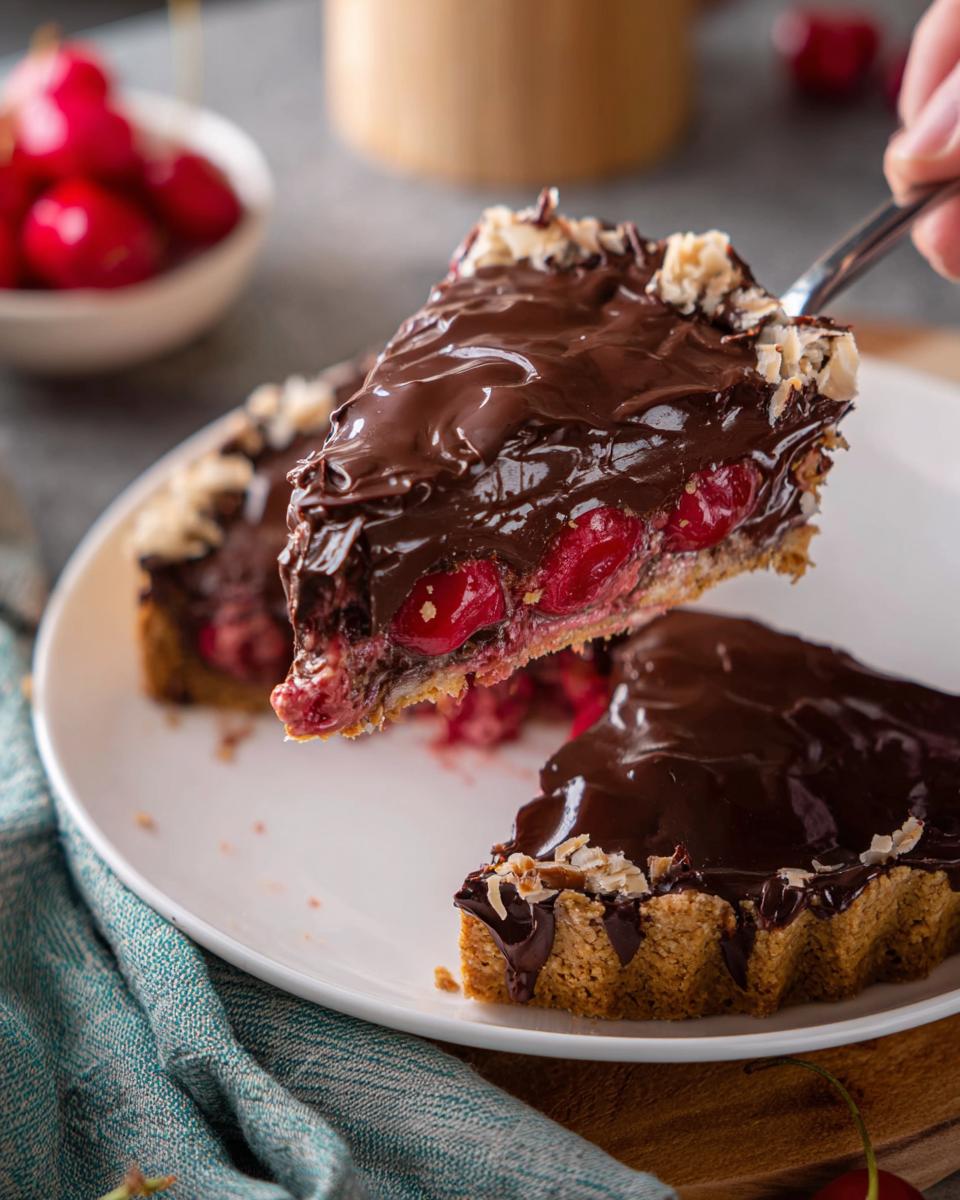 A slice of Cherry Chocolate Ganache Pie being lifted from the plate, showing the rich chocolate topping and cherry filling.