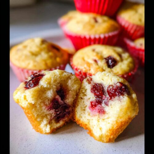 Close-up of a Cherry Yogurt Muffin cut in half showing the soft, moist interior and bright red cherries.