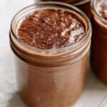 Close-up of creamy Chocolate Blended Overnight Oats topped with cocoa powder in a glass jar.