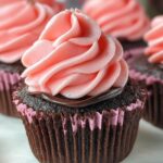 Close-up of a rich chocolate cupcake topped with pink frosting and a chocolate drizzle, perfect for Chocolate Strawberry Valentine Cupcakes.