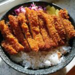A close-up overhead view of a Classic Chicken Katsu Rice Bowl featuring crispy, sliced fried chicken over white rice.