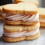 A stack of two heart-shaped Classic Valentine Sandwich Cookies filled with pink vanilla cream.