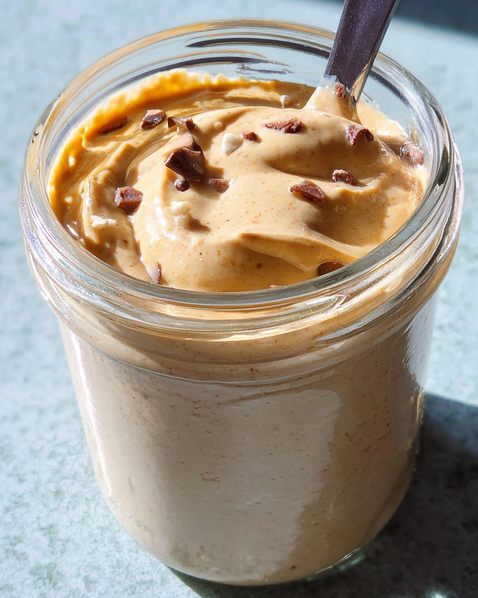 Close-up of thick, creamy blended vanilla overnight oats topped with chocolate shavings in a glass jar.