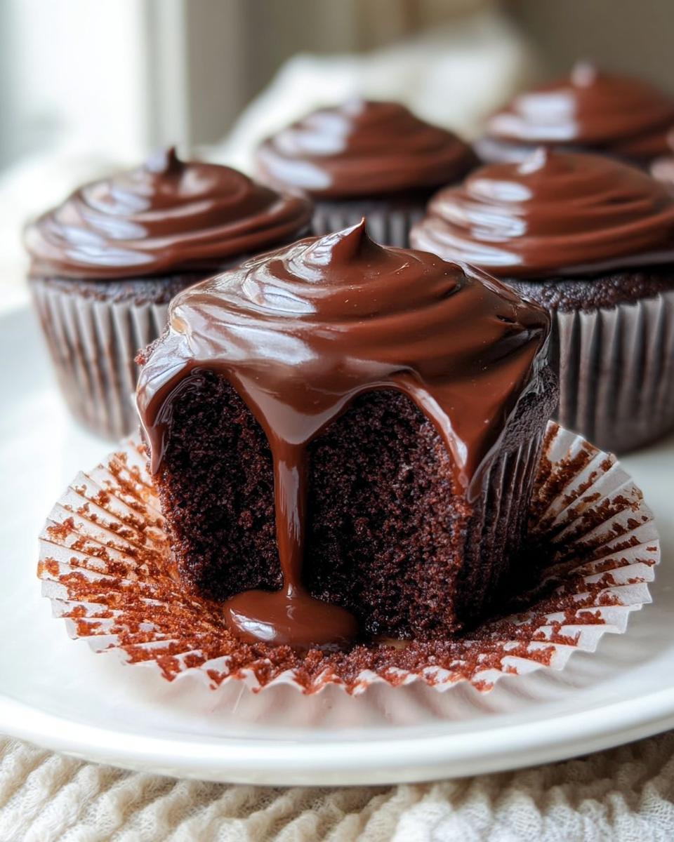 A halved Cupid’s Chocolate Cupcake showing moist dark cake and rich chocolate ganache dripping down the side.