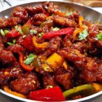 Close-up of glossy, saucy Dragon Chicken with Szechuan Sauce, mixed with colorful bell peppers.
