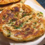 Close-up of a golden-brown, pan-fried Frozen-to-Pan Scallion Pancake with visible green scallions.