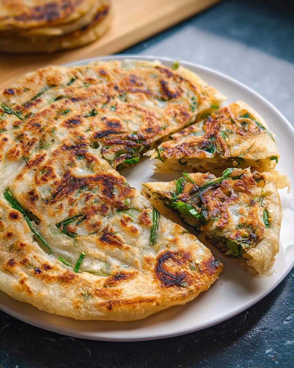 Close-up of a golden, pan-fried Frozen-to-Pan Scallion Pancake cut into wedges on a white plate.