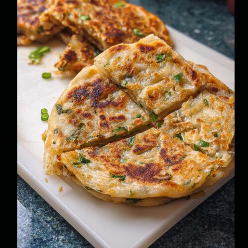 Close-up of golden-brown Frozen-to-Pan Scallion Pancakes, sliced into wedges on a white cutting board.