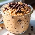 Close-up of Healthy Chocolate Chip Cookie Dough Overnight Oats topped with chocolate chips in a glass jar.
