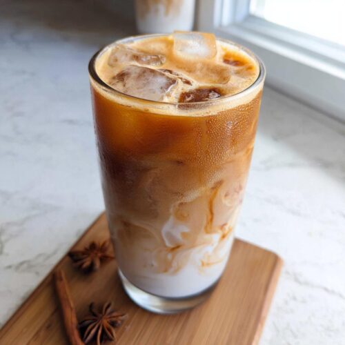 A tall glass of Iced Chai Latte with Brown Sugar showing layers of milk, chai concentrate, and ice cubes.