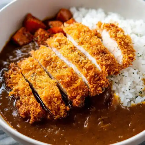 A close-up of a Katsu Bowl with Curry Sauce, featuring sliced crispy fried pork cutlet over rice and rich brown curry sauce.