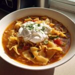 A hearty bowl of Low Fat Lasagna Soup featuring wide noodles, tomato broth, and topped with a large dollop of Greek yogurt or ricotta.