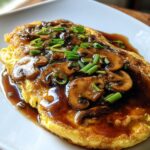 A close-up of Mushroom Egg Foo Young with Oyster Sauce, topped with sliced mushrooms and green onions.