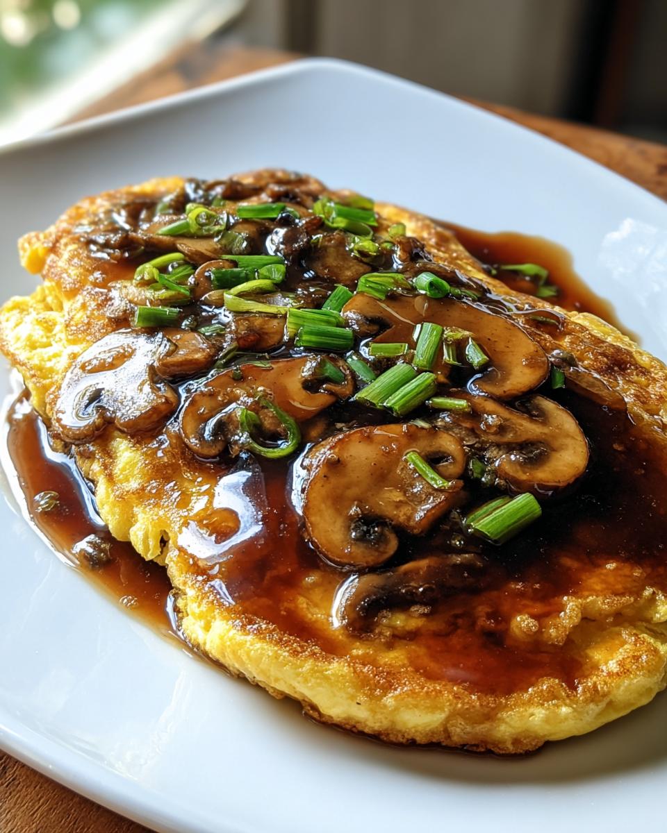 A close-up of Mushroom Egg Foo Young with Oyster Sauce, topped with sliced mushrooms and green onions.