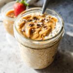 Close-up of Peanut Butter High-Protein Overnight Oats topped with peanut butter swirl and cacao nibs in a glass jar.