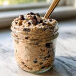 Close-up of Protein Cookie Dough Overnight Oats topped with chocolate chips in a glass jar.