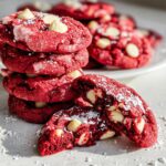 A stack of vibrant Red Velvet Crinkle Cookies with White Chocolate Chips, dusted with powdered sugar.