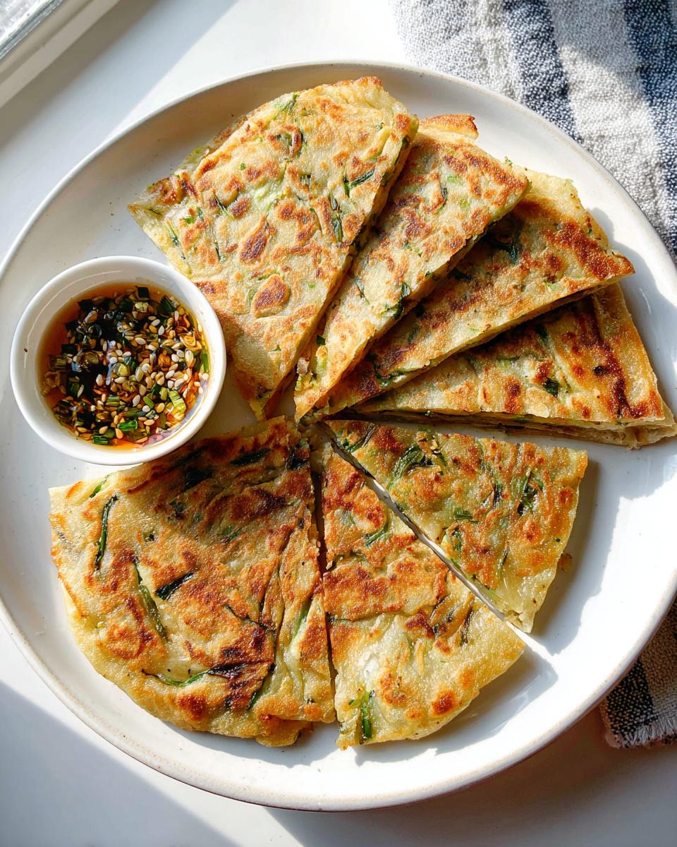 Golden brown Scallion Pancakes with Five-Spice cut into wedges, served with a small bowl of dipping sauce.