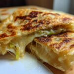 Close-up of a golden-brown Scallion Pancakes Stuffed with Cheese, broken open to show melted, stretching cheese and green scallions.