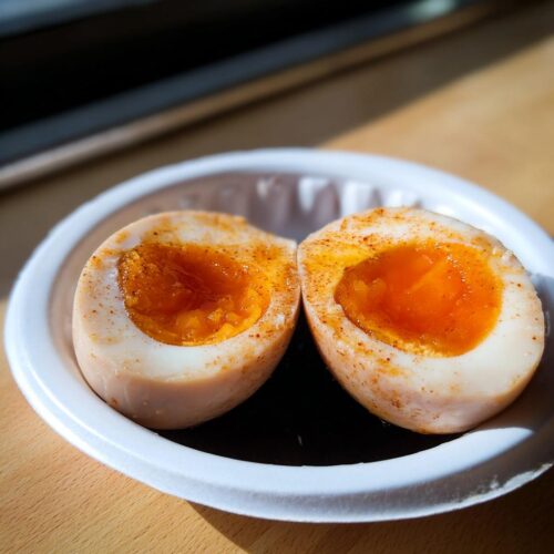 Two halves of Soy Sauce Boiled Eggs showing a bright orange, jammy yolk, seasoned with spices.