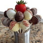 A bouquet of chocolate-dipped strawberries and marshmallows on sticks, featuring white and dark chocolate coatings and sprinkles.