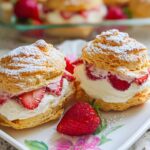 Two Strawberry Puff Pastry Cream Puffs filled with cream and sliced strawberries, dusted with powdered sugar.