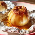 Close-up of a tender, cooked onion sitting in its foil wrapper, ready for the Viral Foil-Wrapped Onion Boil.