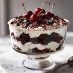 A layered Black Forest Cherry Tiramisu dessert featuring dark chocolate cake, cream, and cherries, topped with fresh cherries.