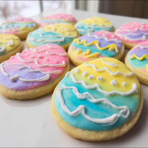 A close-up of several oval-shaped Easter Sugar Cookies with Pastel Icing featuring bright blue, yellow, and pink ombre colors.