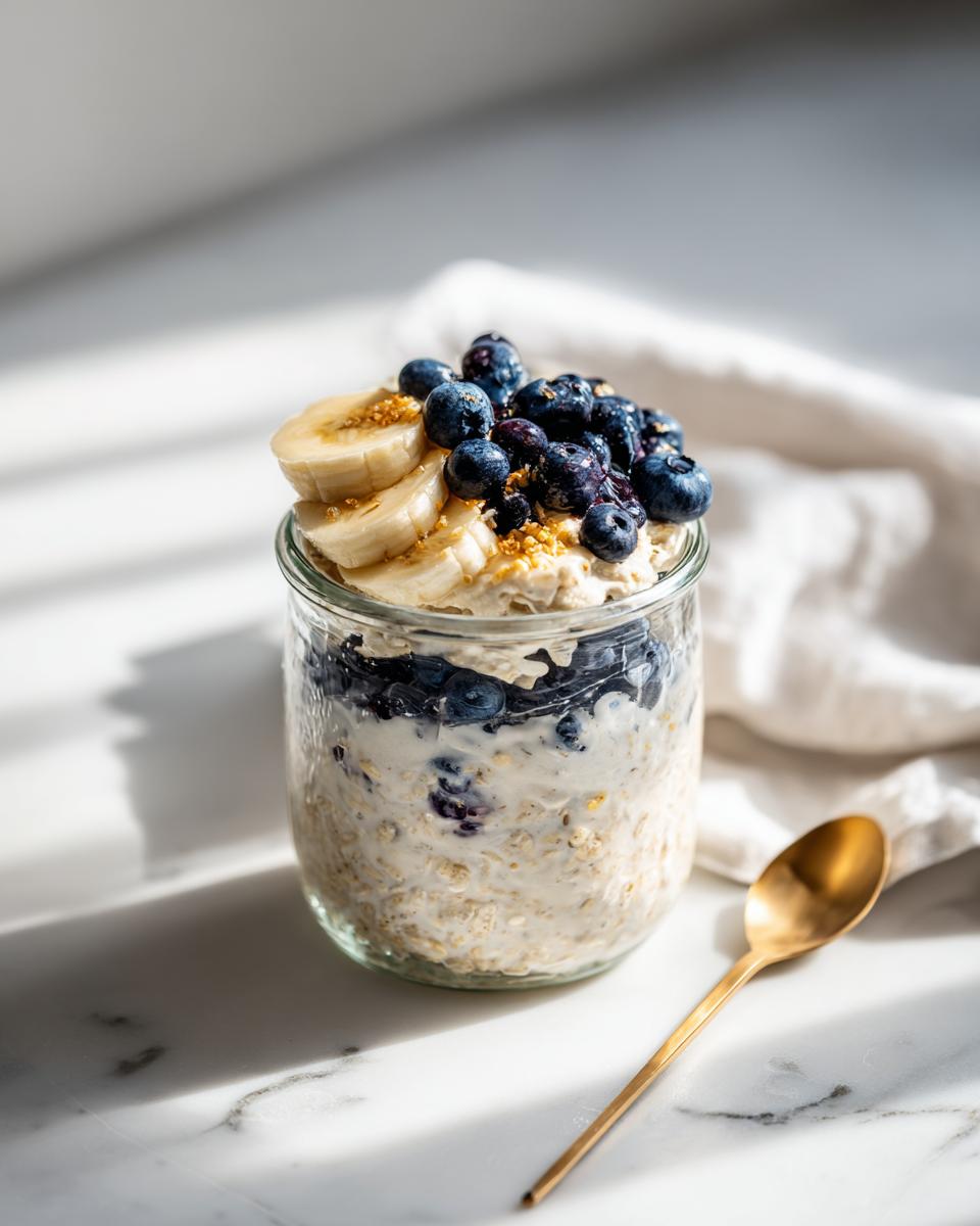 Jar of High Protein Overnight Oats topped with fresh blueberries and banana slices.
