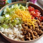 Close-up of a High Protein Turkey Taco Bowl featuring seasoned ground turkey, rice, lettuce, cheese, and tomatoes.