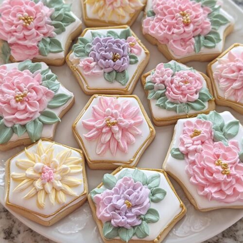 A plate of beautifully decorated Mini Flower Baby Shower Cookies featuring 3D buttercream flowers in pink, purple, and yellow.
