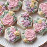 Close-up of hexagon-shaped Mini Flower Baby Shower Cookies decorated with 3D pink, purple, and yellow buttercream flowers.
