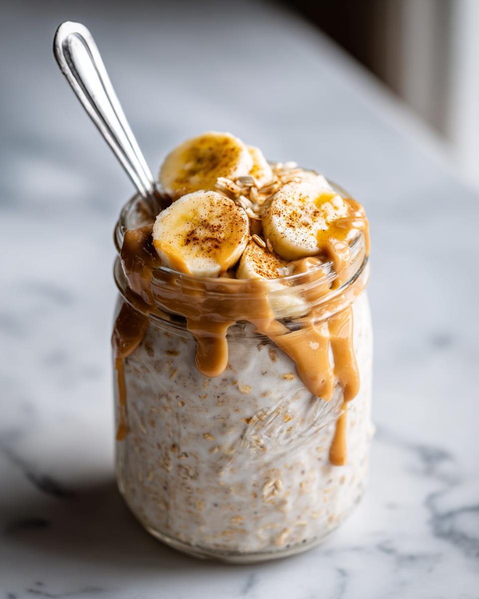 Close-up of Peanut Butter Banana Protein Overnight Oats topped with sliced bananas and drizzled peanut butter.