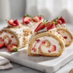 Close-up of sliced Strawberry Cheesecake Rolls with graham cracker crumble and fresh strawberries.
