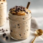 Close-up of Vegan Cookie Dough Overnight Oats topped with peanut butter swirl and chocolate chips in a mason jar.