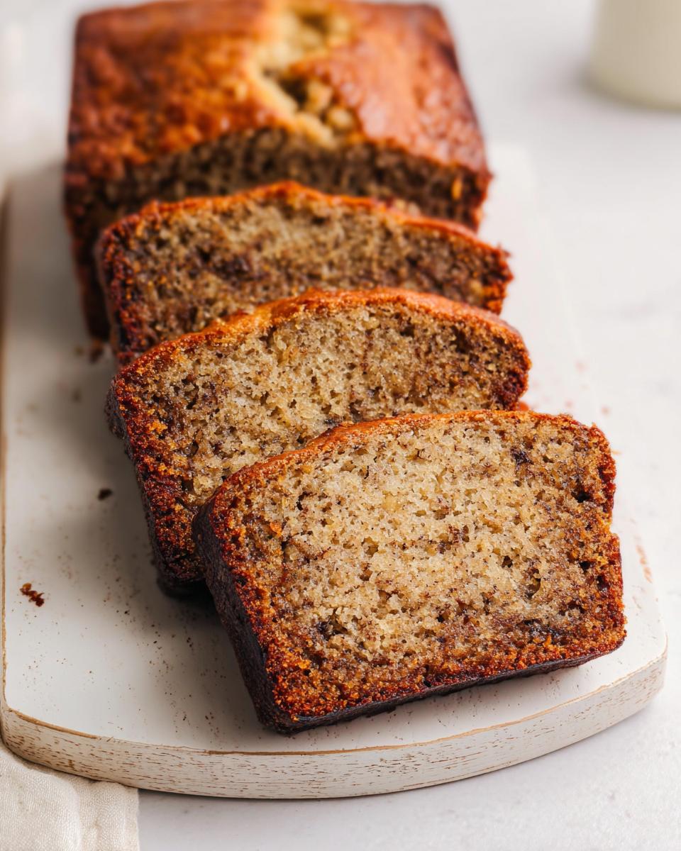 Close-up of three thick slices cut from a loaf of moist Bakery Style Banana Bread, showing a rich, brown crust.