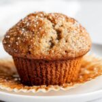 Close-up of a single, perfectly domed Bakery Style Banana Muffins topped with coarse sugar crystals.