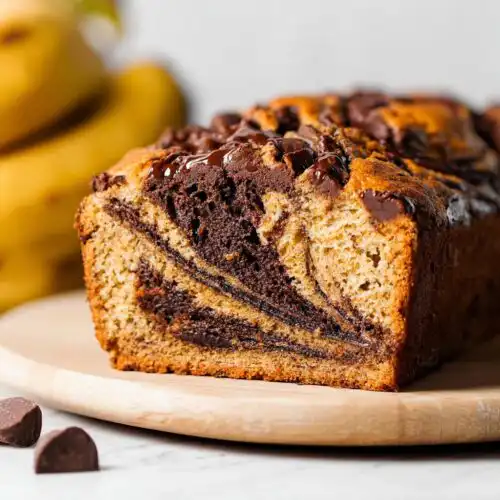 Close-up of a slice of Banana Chocolate Swirl Cake showing rich chocolate marbling and a chocolate chip topping.