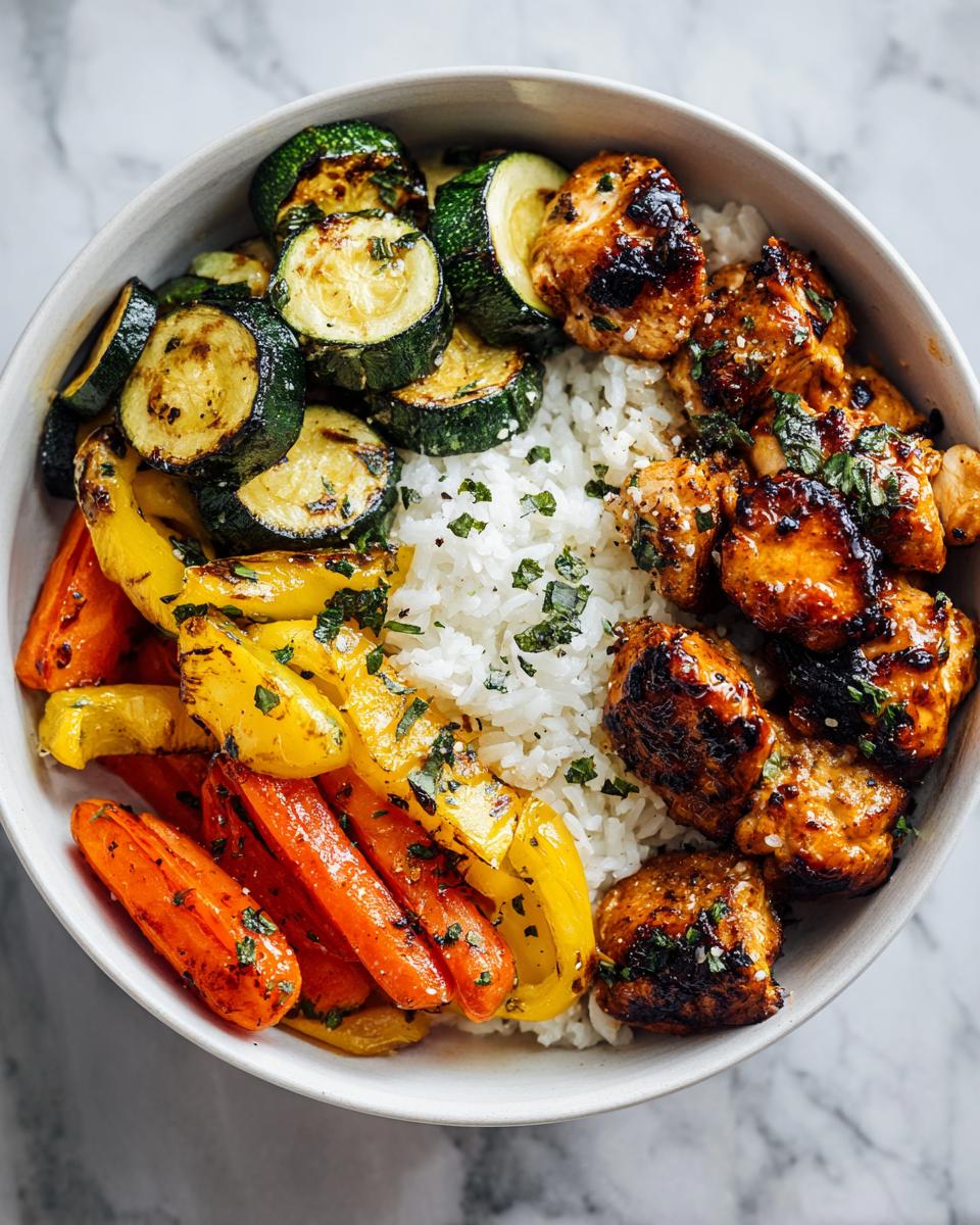 Overhead view of a Chicken Veggie Summer Bowl featuring grilled chicken, rice, zucchini, carrots, and peppers.