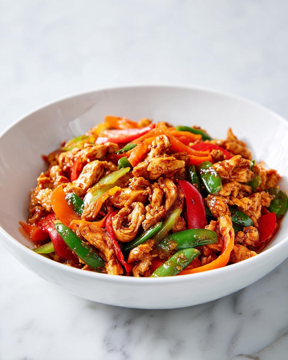 A white bowl filled with shredded chicken and sliced red, orange, and green peppers, perfect for Summer Crockpot Dinner Ideas.