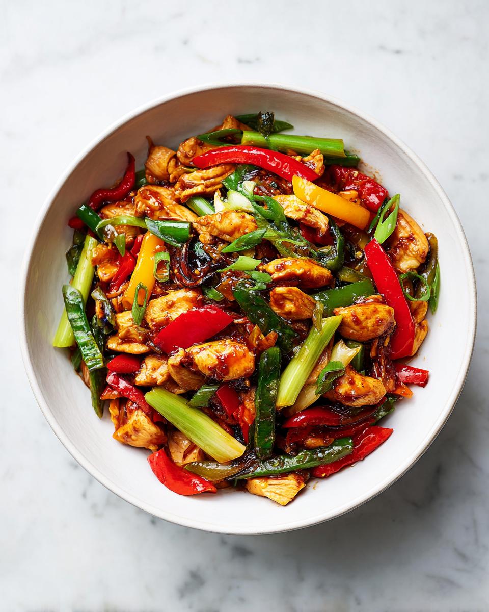 A vibrant bowl of chicken stir-fry with red and yellow peppers and green onions, perfect for Summer Crockpot Dinner Ideas.