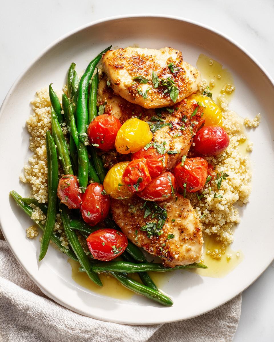 A plate featuring an Easy Healthy Summer Dinner: seared chicken breasts over quinoa with green beans and roasted cherry tomatoes.