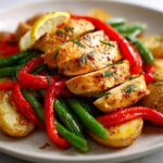 Sliced seasoned chicken breast served with roasted potatoes, red bell peppers, and green beans for an Easy Summer Chicken Dinner.