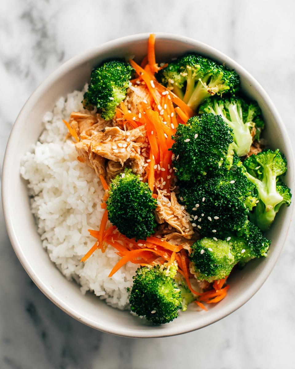 Overhead view of an Easy Summer Dinner Bowl featuring white rice, shredded chicken, bright green broccoli florets, shredded carrots, and sesame seeds.