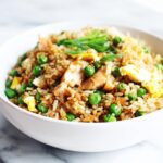 Close-up of a white bowl filled with Easy Summer Rice Dinner, featuring chicken, peas, and scrambled egg.