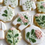 A collection of beautifully decorated Elegant Garden Baby Shower Cookies featuring floral designs and baby onesie shapes.