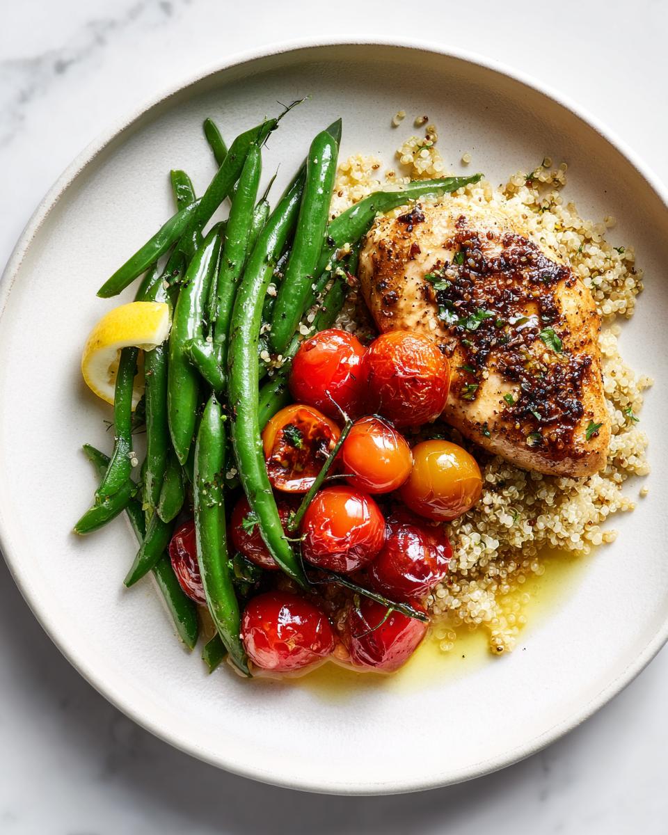 Overhead view of a Fresh Summer Chicken Plate featuring seasoned chicken breast, green beans, roasted cherry tomatoes, and quinoa.